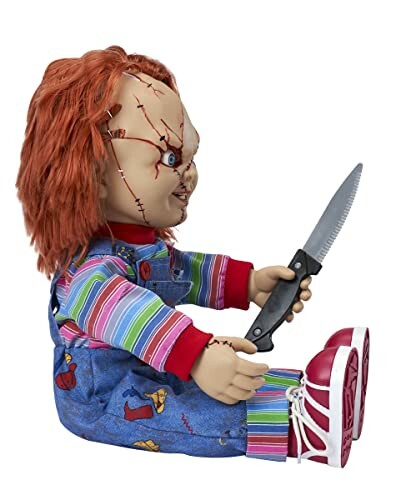 Chucky doll holding a knife, sitting in colorful overalls.