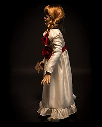 Side view of a creepy doll in a white dress with red accents.