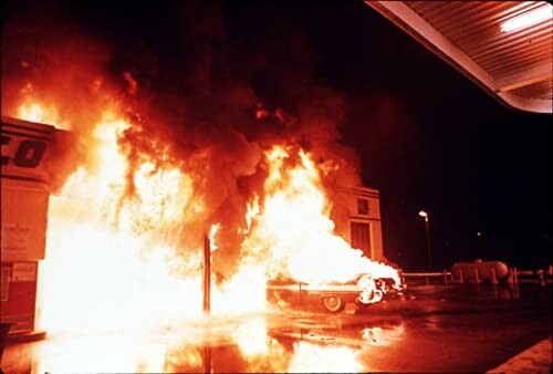 Gas station engulfed in large flames at night.