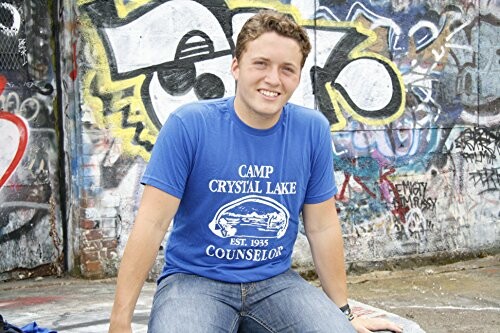 Man in blue shirt sitting by a graffiti-covered wall.