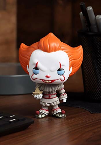 Funko Pop figurine of a clown with orange hair on a desk.