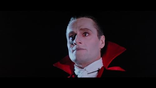 Vampire character with red collar in dark setting.